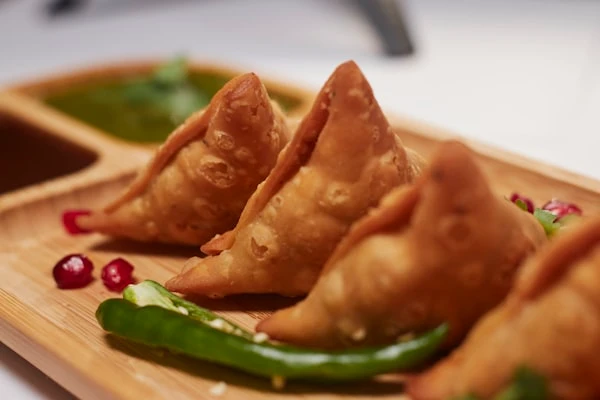 Samosa Chaat — Crushed samosa, yoghurt, three chutneys
